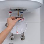 plumber holds a thermostat from water