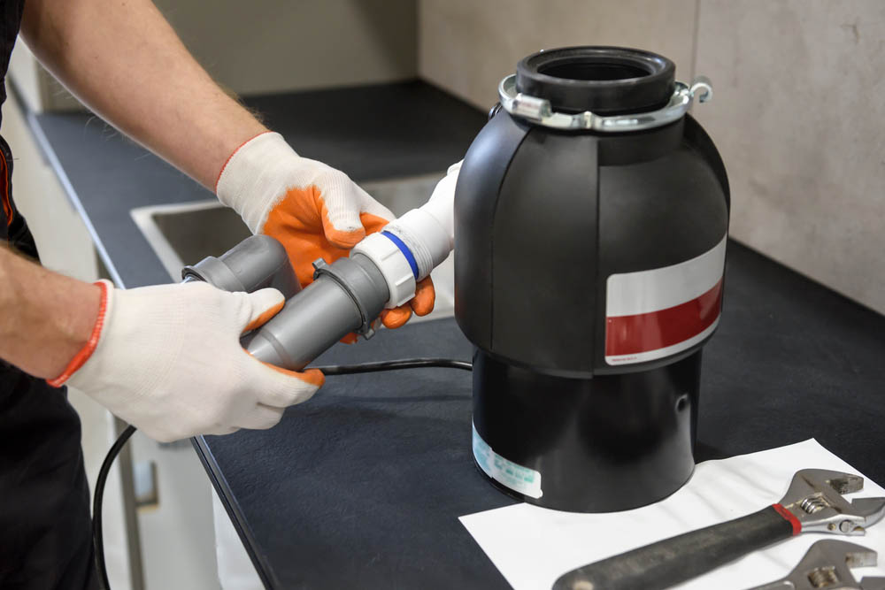 plumber installing a garbage disposal unit